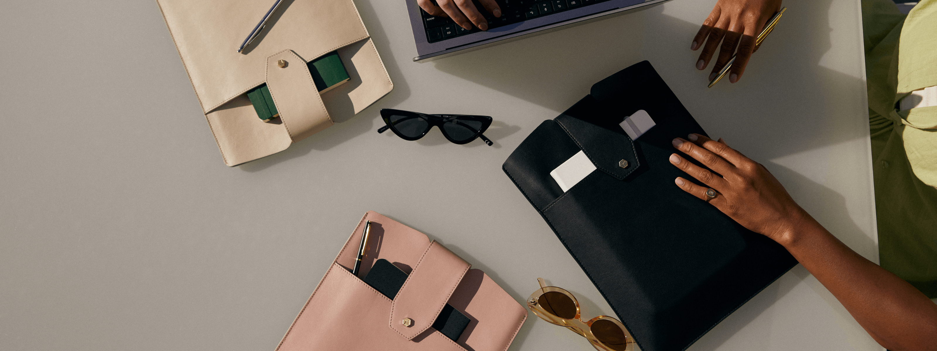 Stylish folders, sunglasses, and a laptop on a table, showcasing modern workspace accessories.
