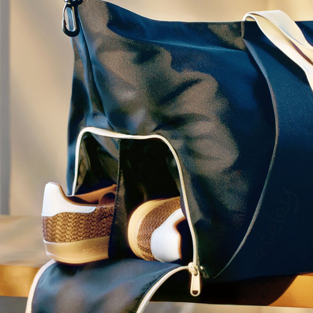 Navy duffel bag with a brown and white sneaker inside, on a wooden surface.