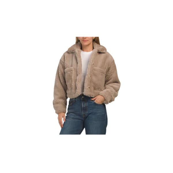 Woman wearing a cozy cropped beige sherpa jacket with pockets and classic blue jeans.