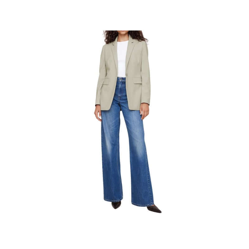Woman wearing a stylish light gray blazer with wide-leg blue jeans, combining casual and chic fashion.
