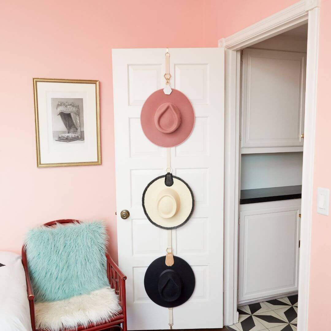 Three hats organized on a door using The Collector Hat Organizer, showcasing efficient storage solution.