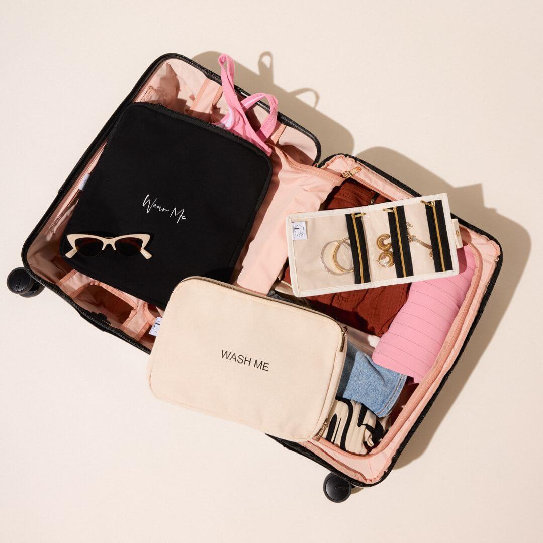 Two-sided travel laundry bag in a packed suitcase with clothes, tan sunglasses, and jewelry pouch, ideal for separating clean and dirty laundry.