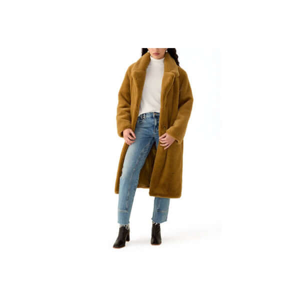 Woman wearing a stylish brown oversized coat, white turtleneck, and blue jeans with ankle boots.