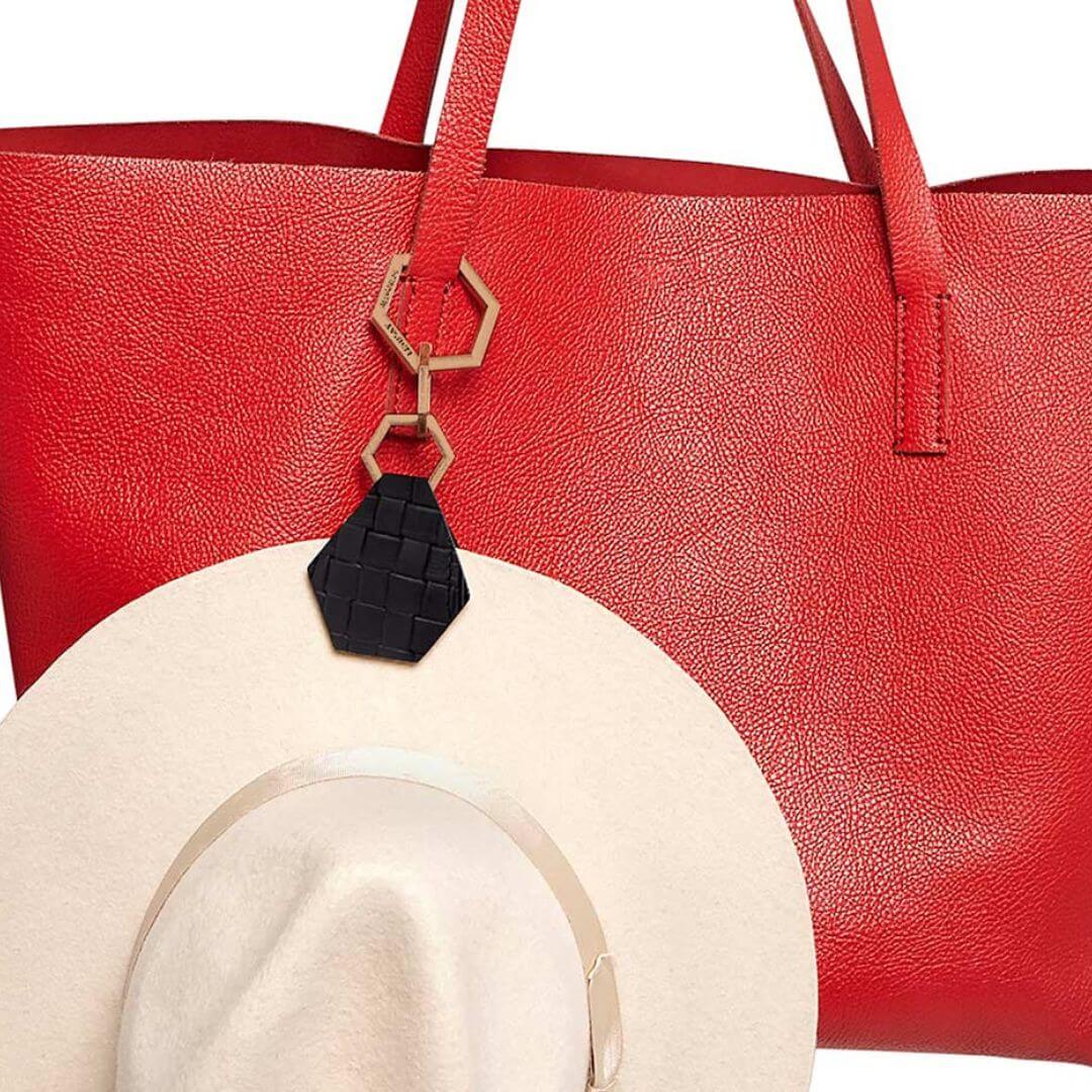 Hex TOPTOTE by Lindsay Albanese magnetic hat clip with gold hardware and genuine leather attached to white fedora hat on a red bag.