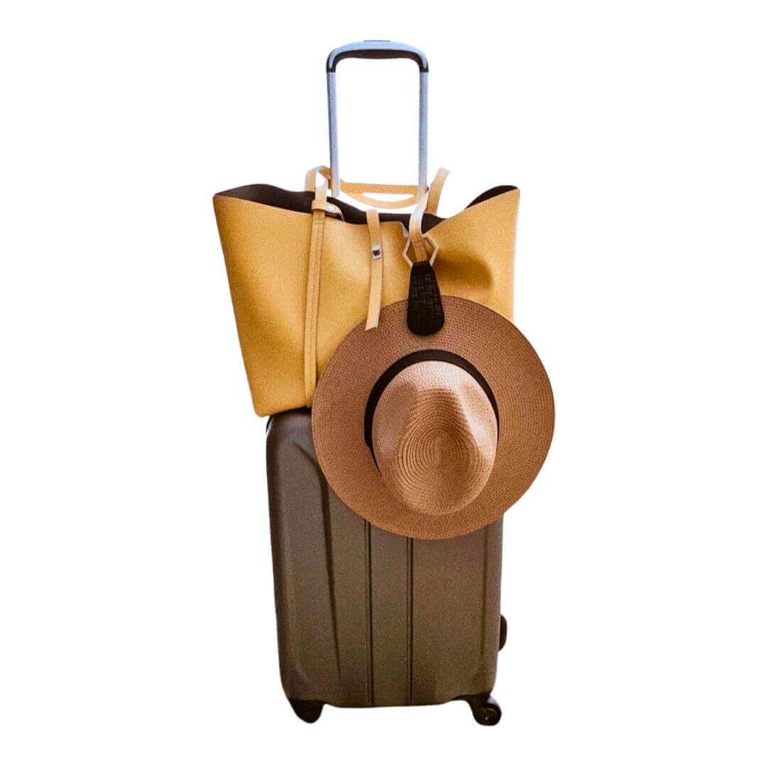 Stylish luggage with a tote bag and a brown sun hat, perfect for travel accessories.