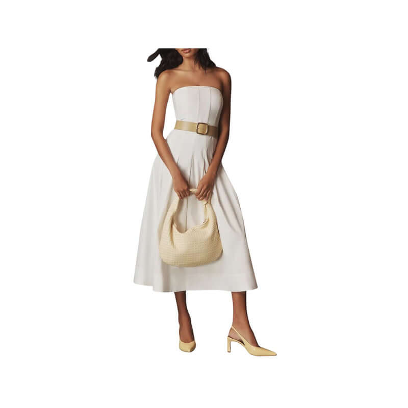 Woman in a stylish white strapless dress holding a yellow handbag and wearing matching heels.