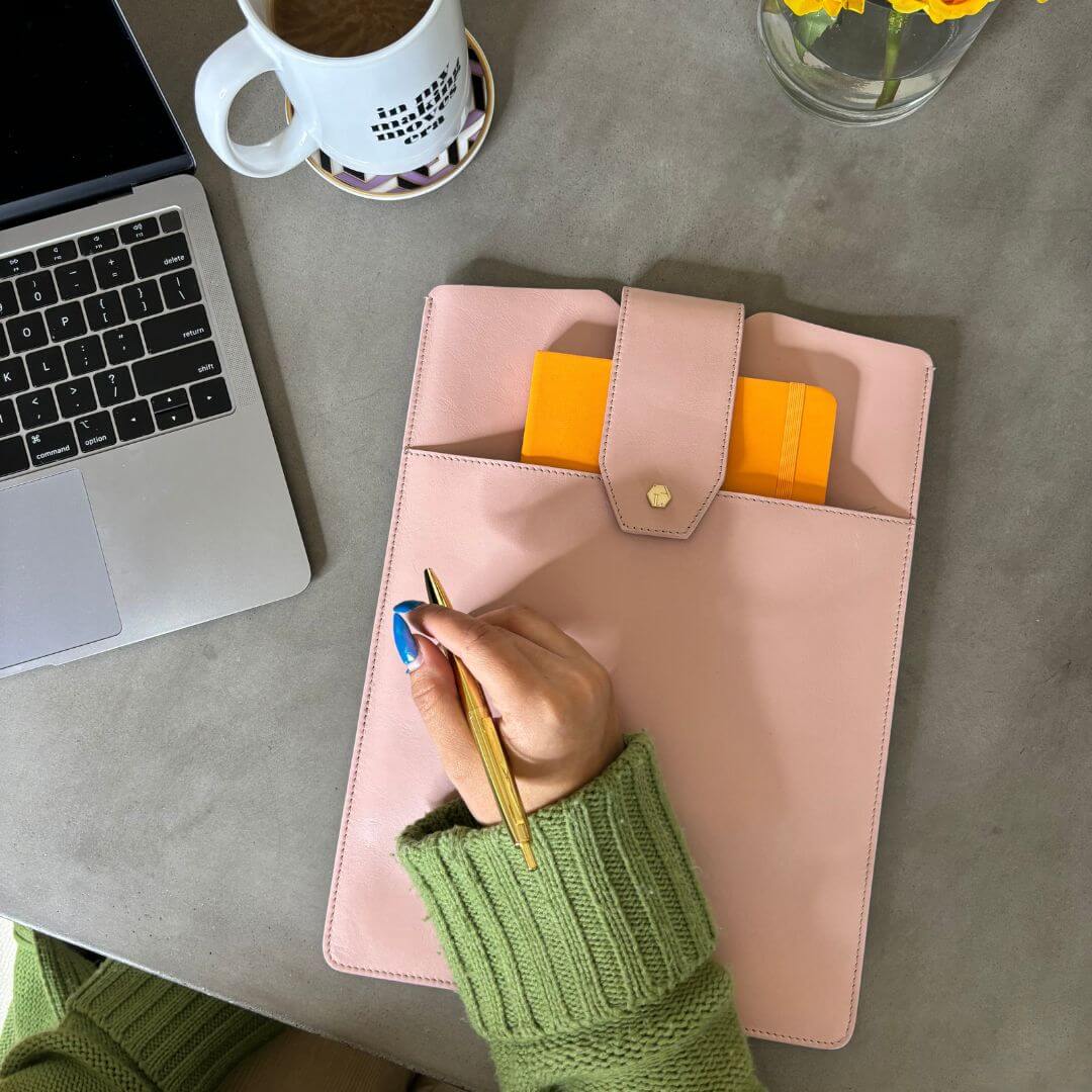 Lindsay Albanese blush laptop sleeve on a desk working on a laptop. 