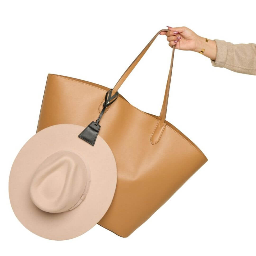 Black Lasso TOPTOTE hat clip holding a beige hat and attached to a tan tote.