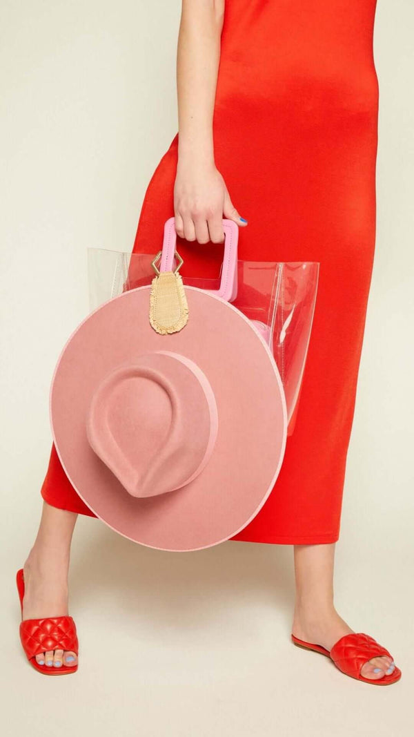 A woman in a red dress holding a stylish pink round handbag with a clear tote, showcasing trendy summer fashion.