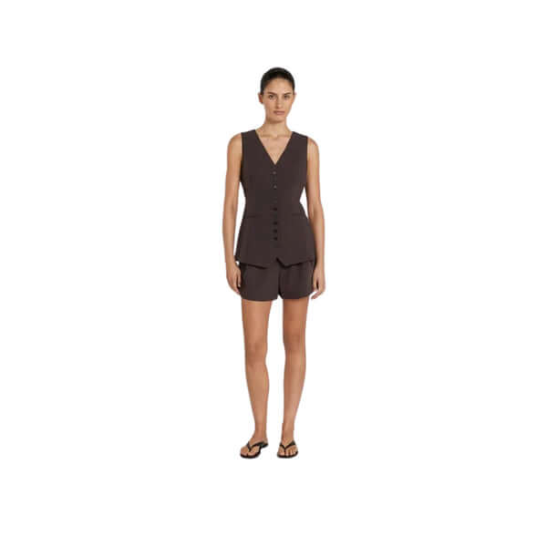 Model wearing a stylish brown sleeveless top and shorts, complemented with flip-flops, against a plain background.