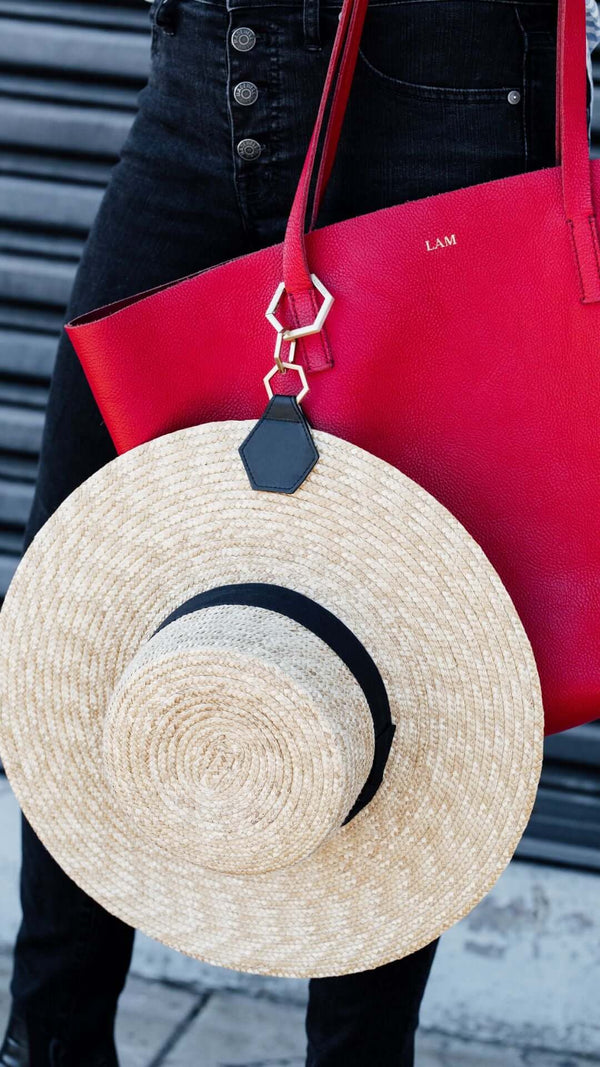 Stylish straw hat resting on a red handbag, perfect for a chic summer look.